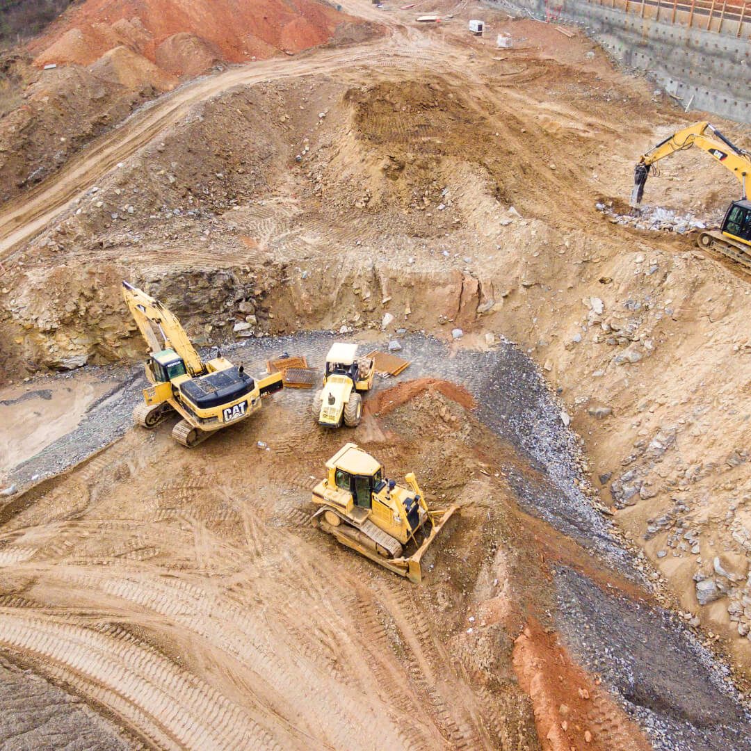 Construction site with excavators and dirt mounds.