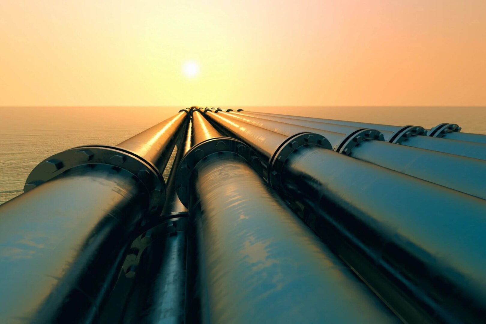 Pipelines stretching towards sunset over water.